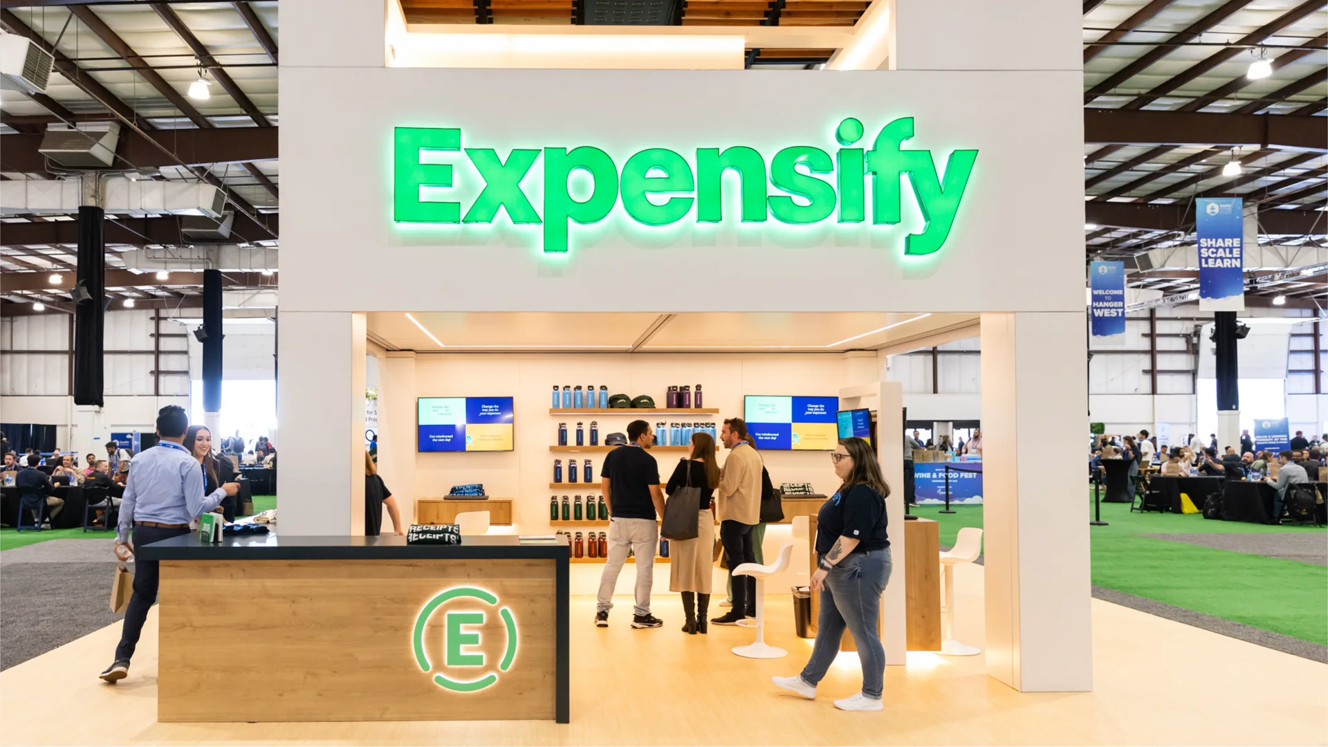 Expensify booth at a company event with the illuminated Expensify wordmark